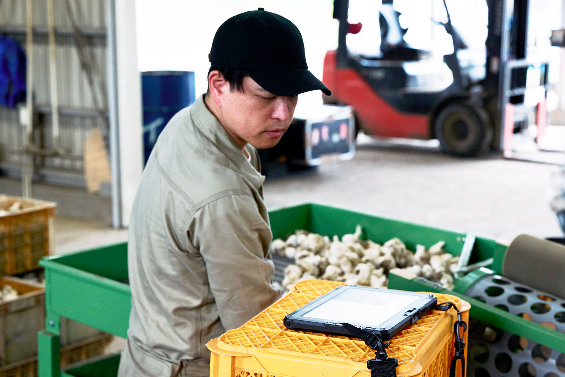A farmer monitors the work performed by the New Agri Robo Tractor while tending to other tasks within a facility.